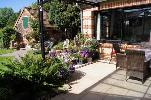a patio with flowers and plants on a house at Le Paddock Du Val De Lys in Blessy