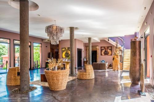 a lobby with pillars and chairs and a chandelier at Hotel restaurant Spa Disini Montpellier Est, The Originals Relais in Castries