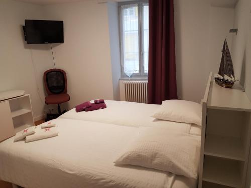 Schlafzimmer mit einem weißen Bett und einem TV in der Unterkunft Hotel du Lac Grandson in Grandson