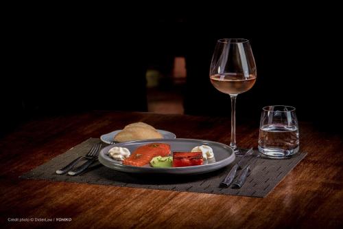 a plate of food and a glass of wine on a table at Hotel restaurant Spa Disini Montpellier Est, The Originals Relais in Castries