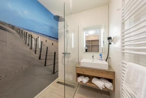 a bathroom with a sink and a glass shower at Beachhotel Zandvoort by Center Parcs in Zandvoort