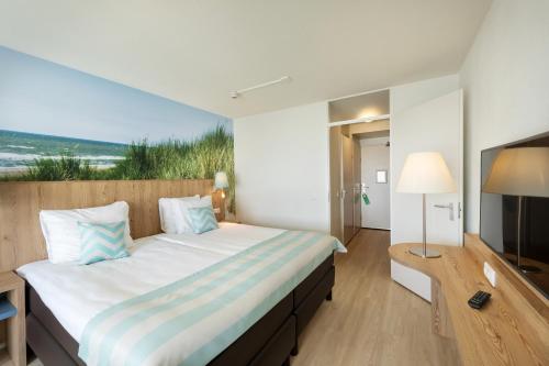 a hotel room with a large bed and a television at Beachhotel Zandvoort by Center Parcs in Zandvoort