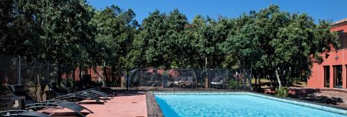 a swimming pool with chairs and trees and a building at Hotel restaurant Spa Disini Montpellier Est, The Originals Relais in Castries
