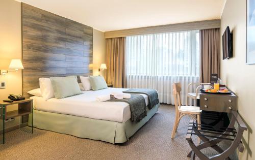 a hotel room with a bed and a table and a desk at Hotel Frontera Plaza in Temuco