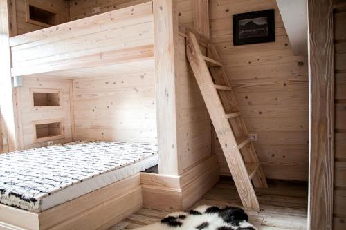 a wooden bed in a wooden room with a ladder at Apartament Pod Modrzewiami in Szczawnica