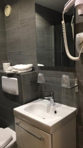 une salle de bain avec un lavabo blanc et un miroir dans l'établissement Hôtel du Maine, à Paris