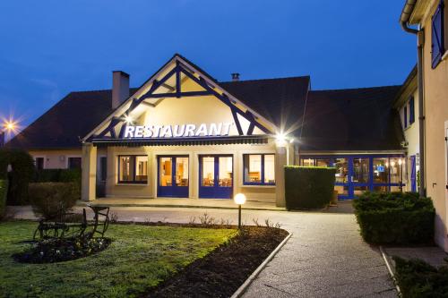 a building with a sign for a restaurant at night at Comfort Hotel Etampes in Étampes
