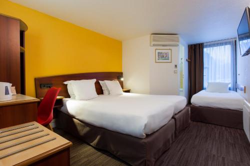 Pokój hotelowy z 2 łóżkami i biurkiem w obiekcie Comfort Hotel Etampes w mieście Étampes