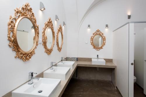ein Bad mit 3 Waschbecken und Spiegeln an der Wand in der Unterkunft Lost Inn Lisbon Hostel in Lissabon