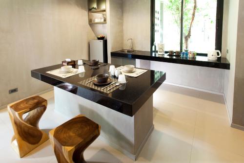a kitchen with a black counter and wooden chairs at Villa Thalanena By The Beach in Tha Lane Bay