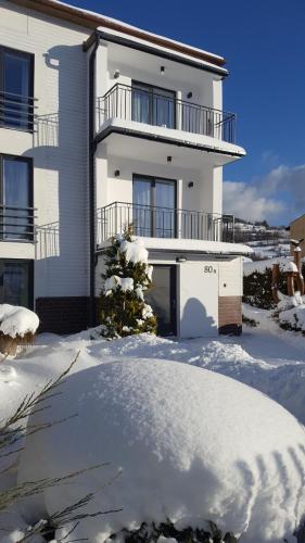 a white house with snow in front of it at Willa Karo in Muszyna