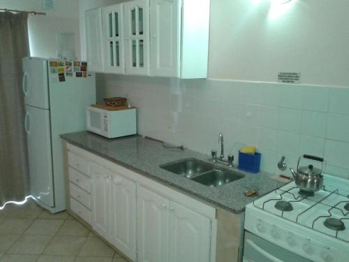 Una cocina con fregadero y refrigerador blanco. en Playa Shaw 497, en Pinamar