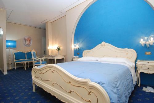 a bedroom with a large bed with a blue wall at Hotel Il Burchiello in Mira
