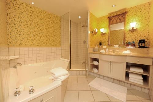 a bathroom with a tub and a sink and a mirror at Old Mill Toronto Hotel in Toronto
