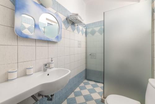 een badkamer met een wastafel, een toilet en een spiegel bij Kozas Superior Apartments in Archangelos