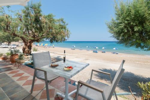 a table and chairs on a patio with a beach at Kozas Superior Apartments in Archangelos