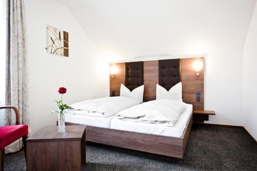 a bedroom with a large bed and a red chair at Gasthaus Bürger-Stube in Sasbach am Kaiserstuhl