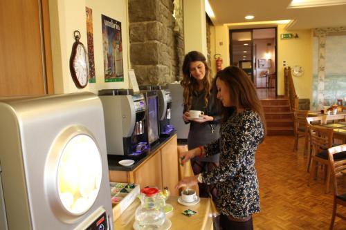 two women standing at a counter with a cup of coffee at Hotel Vega Perugia in Perugia