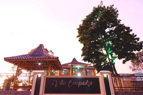 a sign in front of a building with a tree at Villa Cempaka Pangalengan in Cibeureum