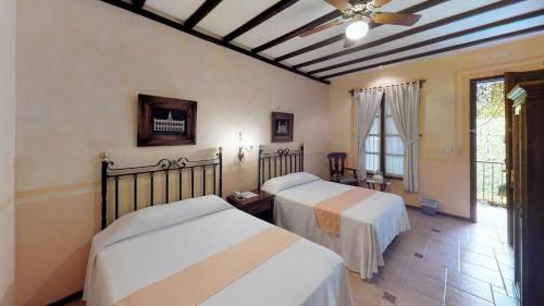 a bedroom with two beds and a ceiling fan at Hotel Boutique La Mision De Fray Diego in M&eacute;rida