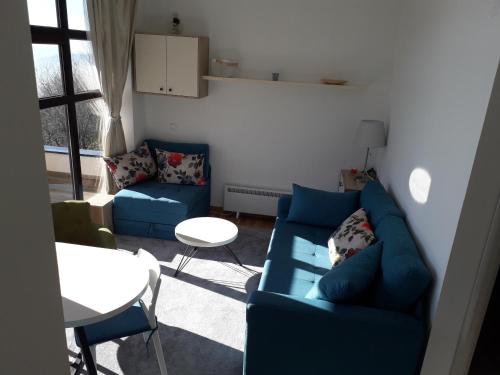 a living room with a blue couch and a table at Apartman D52 Dvori in Kopaonik