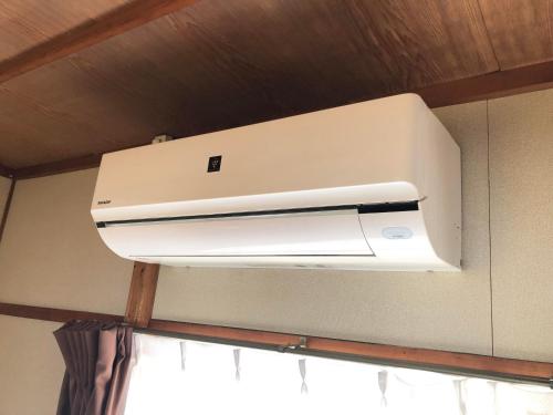 a white air conditioner hanging from a ceiling at カモンイン 寿 in Izumi