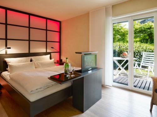 a bedroom with a bed with a desk and a television at Landhaushotel Hof Wasserkuppe in Poppenhausen