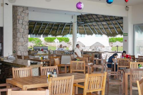 a restaurant with wooden tables and chairs and people in the background at BSEA Cancun Plaza Hotel in Cancún