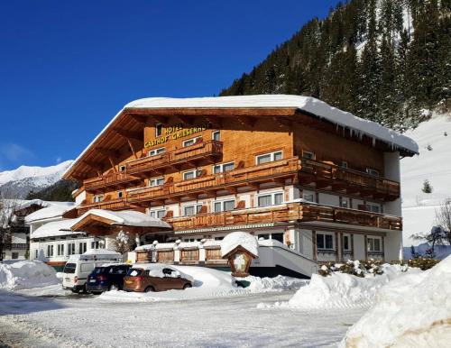 a large building with cars parked in the snow at Hotel Grieserhof in Lermoos