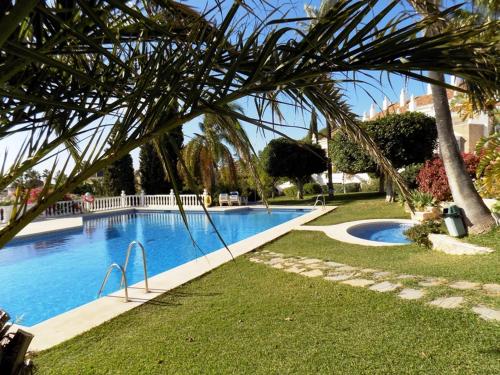 una gran piscina con una palmera en un patio en Apartament - dom, Hiszpania Andaluzja, Costa del Sol, en Estepona