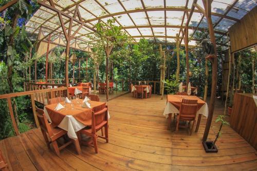 un restaurant avec des tables et des chaises sur une terrasse en bois dans l'établissement Hotel Wagelia Espino Blanco, à Turrialba