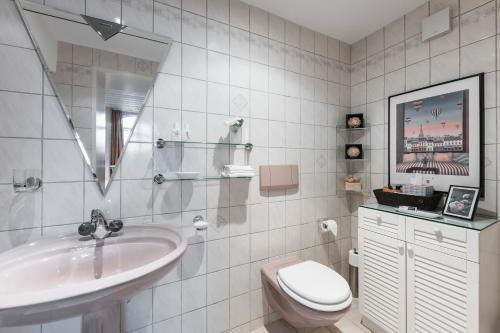 uma casa de banho branca com um lavatório e um WC em Art Deco Villa Mon Abri BnB em Goldau