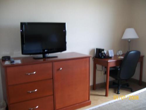 a television on a dresser with a desk and a chair at Days Inn by Wyndham Moose Jaw in Moose Jaw