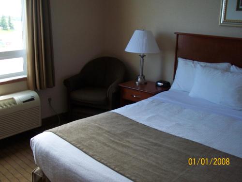 a hotel room with a bed and a chair and a window at Days Inn by Wyndham Moose Jaw in Moose Jaw