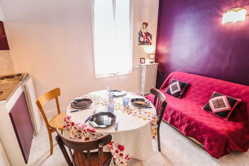 a living room with a table and a red couch at La Roseraie in Lodève