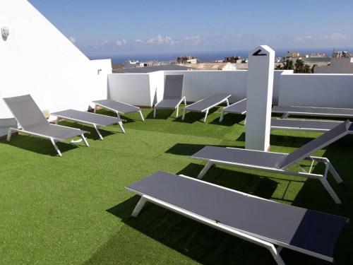 une rangée de chaises et de tables sur un toit dans l'établissement Apartamentos cerca del Aeropuerto, à Ingenio