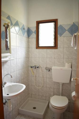 a bathroom with a toilet and a sink at NIKIS ROOMS in Kalamakia