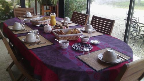 Feugarolles的住宿－les tilleuls de la voie verte，餐桌上带紫色桌布的桌子,带食物