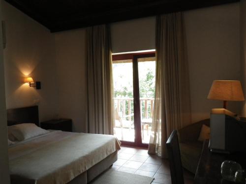 um quarto com uma cama e uma janela grande em Hotel Rural Quinta de Novais em Arouca
