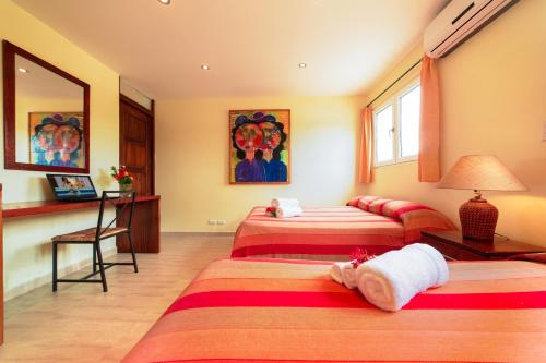 a hotel room with three beds and a desk at Hotel Las Palmeras in Sosúa