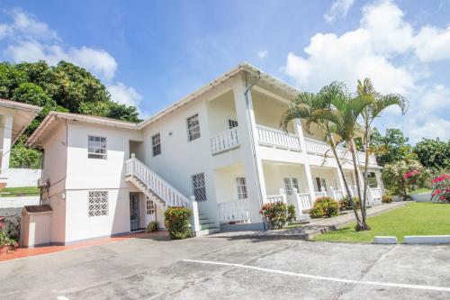 a large white house with a palm tree at Rosewood Apartment Hotel in Arnos Vale