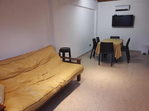 Duplex en Valle Hermoso في فالي هيرموسو: غرفة معيشة مع أريكة وطاولة مع كراسي