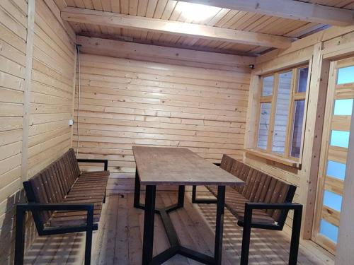 a wooden table and two benches in a room at Забаганка in Mykulychyn