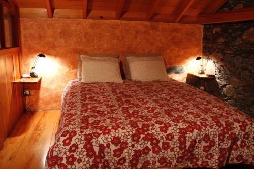 a bedroom with a bed with a red and white bedspread at Casa Rural Finca la Maleza in Agulo