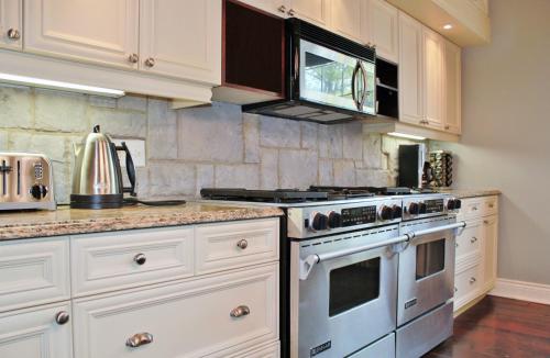 a kitchen with white cabinets and a stove top oven at All Suites Whitney Manor in Kingston