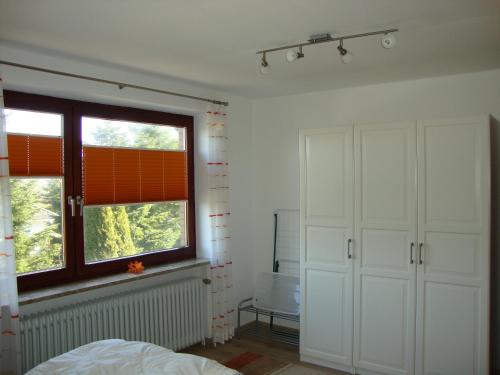 ein Schlafzimmer mit weißen Schränken, einem Fenster und einem Bett in der Unterkunft Ferienwohnung Quaiser in Cuxhaven