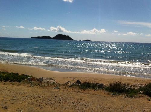 a sandy beach with an island in the ocean at Eleni Apartments in Arillas