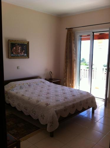 a bedroom with a bed and a sliding glass door at Eleni Apartments in Arillas