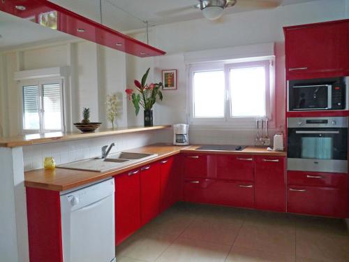 a kitchen with red cabinets and a white stove top oven at Ti ' Plage in Les Trois-Îlets