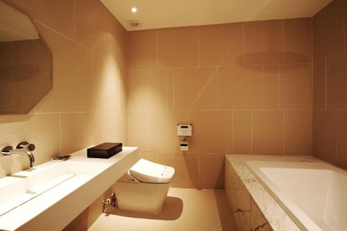 a bathroom with a toilet and a sink and a tub at Urban Boutique Hotel in Anyang